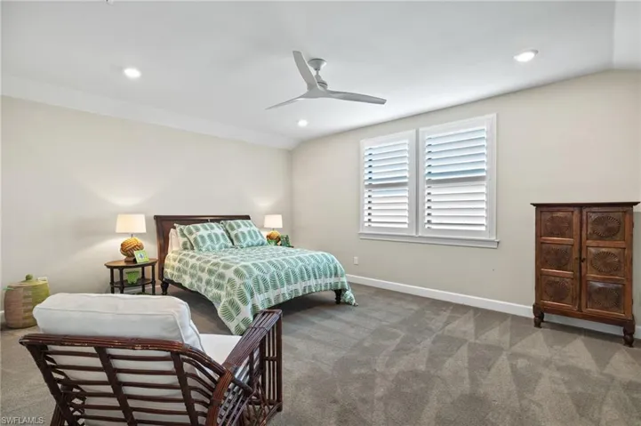 Bedroom featuring dark carpet, ceiling fan, and lofted ceiling