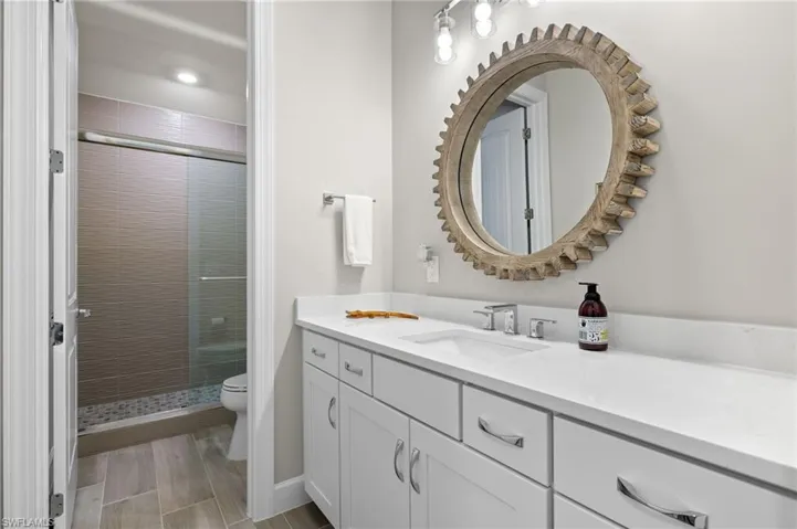 Bathroom featuring a shower with door, vanity, and toilet