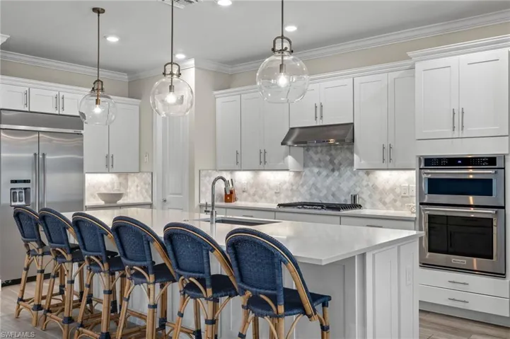 Kitchen featuring appliances with stainless steel finishes, sink, backsplash, and a center island with sink