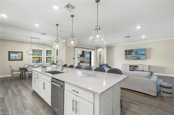 Kitchen featuring white cabinetry, an island with sink, decorative light fixtures, sink, and dishwasher