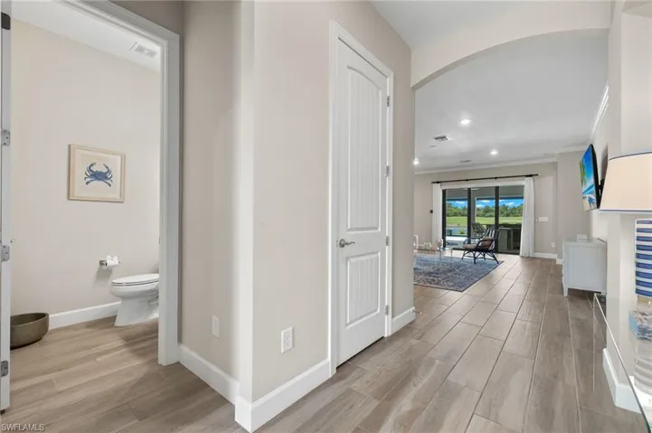 Corridor with ornamental molding and light wood-type flooring