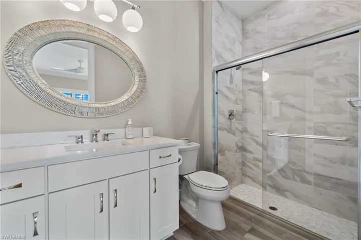 Bathroom featuring walk in shower, toilet, and vanity with extensive cabinet space