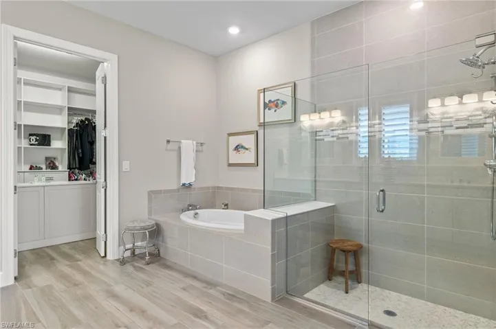 Bathroom with wood-type flooring, separate shower and tub, and vanity