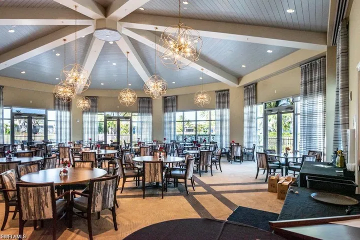 Carpeted dining area with beam ceiling, a high ceiling, a chandelier, and french doors