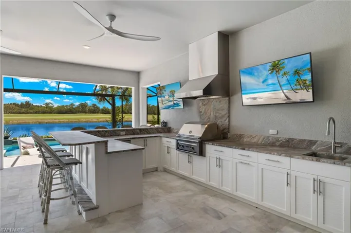 Kitchen featuring white cabinetry, a water view, wall chimney exhaust hood, sink, and light tile flooring