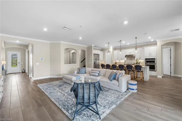 Living room with ornamental molding and light hardwood / wood-style floors