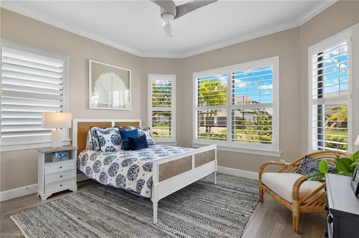 Bedroom featuring crown molding, hardwood / wood-style floors, multiple windows, and ceiling fan