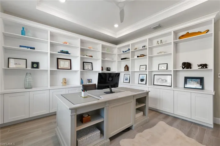Office area featuring ornamental molding, light hardwood / wood-style flooring, and a raised ceiling