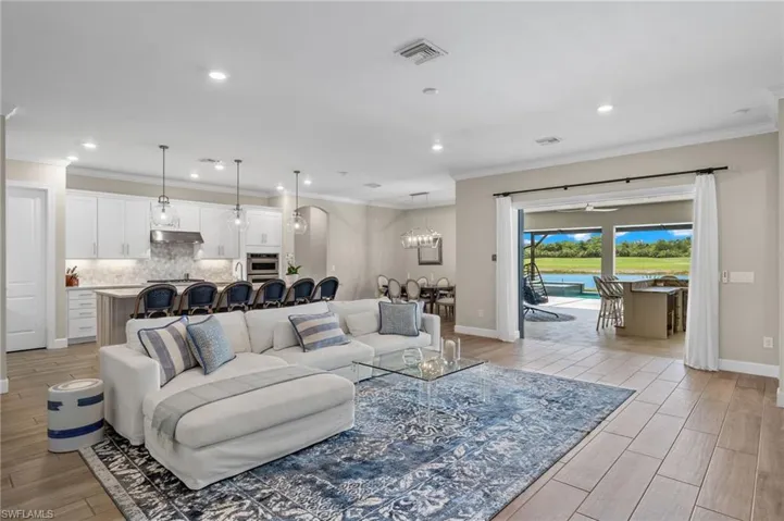 Living room with light hardwood / wood-style floors, crown molding, and a chandelier
