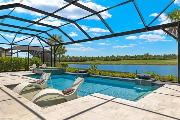 View of pool featuring a patio, glass enclosure, an in ground hot tub, and a water view