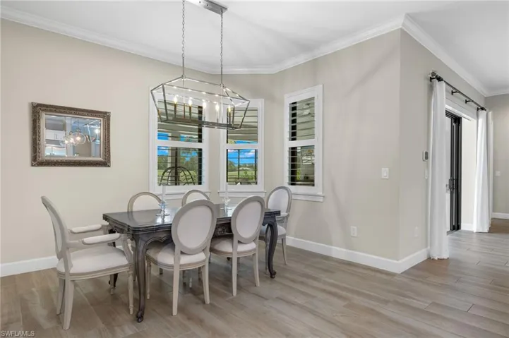 Dining area with light hardwood / wood-style floors, crown molding, and a chandelier