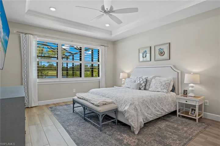 Bedroom featuring crown molding, hardwood / wood-style flooring, ceiling fan, and a raised ceiling