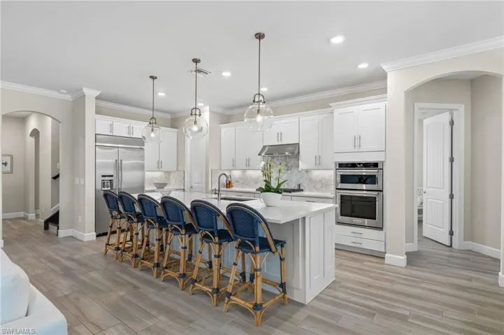 Kitchen with stainless steel appliances, tasteful backsplash, a breakfast bar area, an island with sink, and pendant lighting