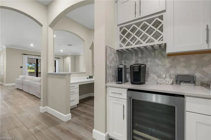 Kitchen with beverage cooler, light hardwood / wood-style floors, tasteful backsplash, and white cabinetry