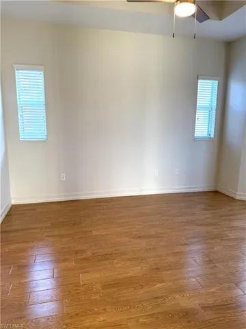 Empty room with a ceiling fan, plenty of natural light, and wood-type flooring