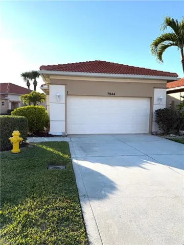 Ranch-style home with concrete driveway, an attached garage, a tiled roof, stucco siding, and a front lawn
