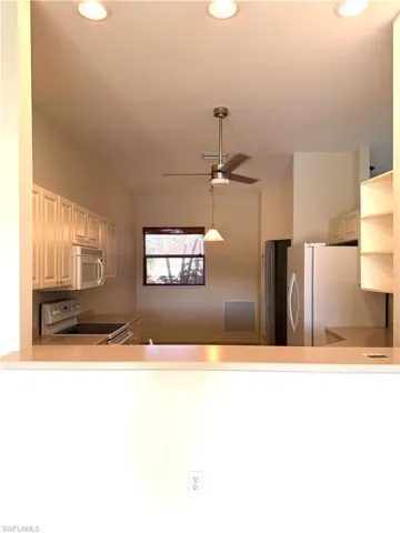 Kitchen featuring light countertops, white appliances, a ceiling fan, and a peninsula