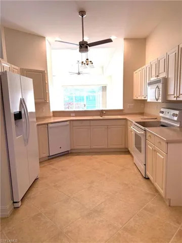 Kitchen featuring white appliances, light countertops, ornamental molding, and light tile patterned flooring