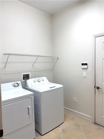 Laundry area featuring washing machine and dryer and light tile patterned floors