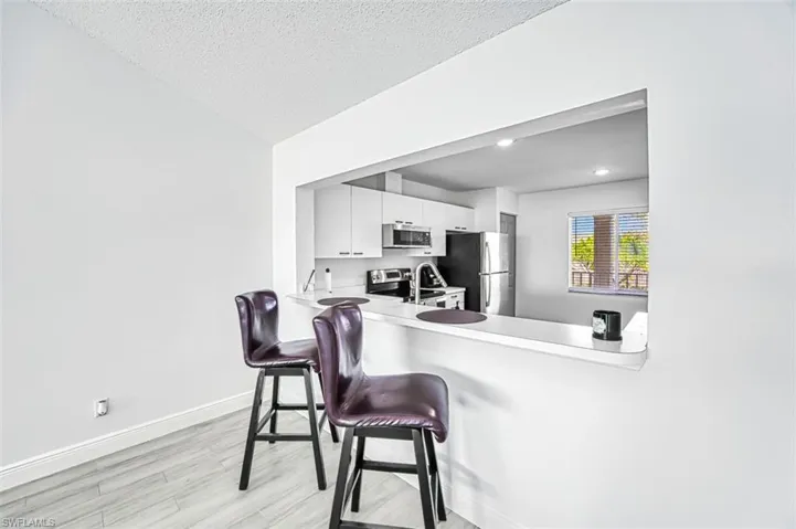 Kitchen featuring white cabinetry, stainless steel appliances, a kitchen breakfast bar, light hardwood / wood-style flooring, and kitchen peninsula