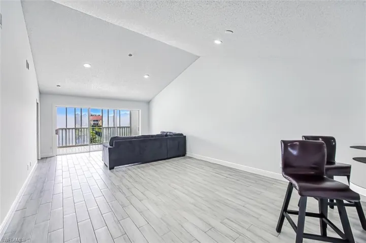 Living room featuring a textured ceiling, light hardwood / wood-style floors, and lofted ceiling