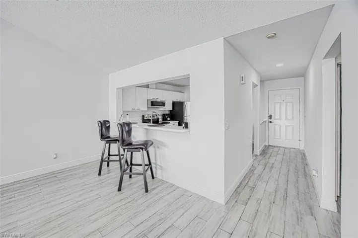 Hallway featuring a textured ceiling, sink, and light hardwood / wood-style flooring