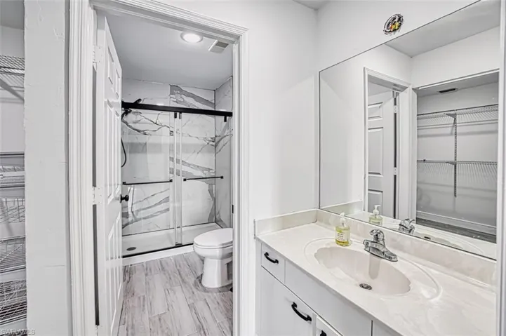 Bathroom with vanity, wood-type flooring, an enclosed shower, and toilet