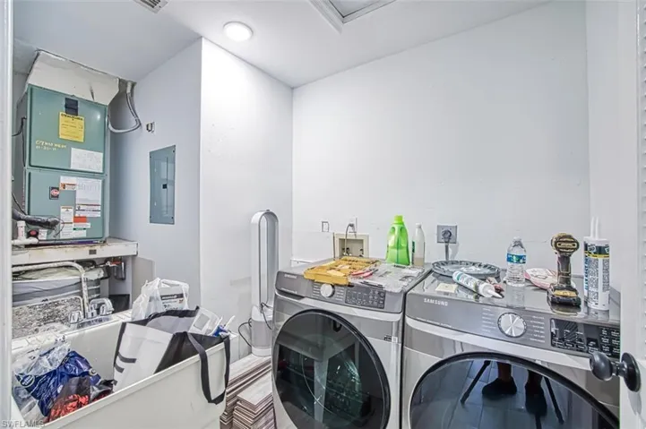 Laundry room with washing machine and clothes dryer, electric panel, and heating unit