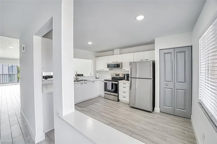 Kitchen with sink, light hardwood / wood-style flooring, white cabinets, and appliances with stainless steel finishes
