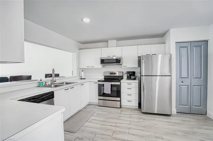 Kitchen with light hardwood / wood-style floors, white cabinetry, sink, and appliances with stainless steel finishes