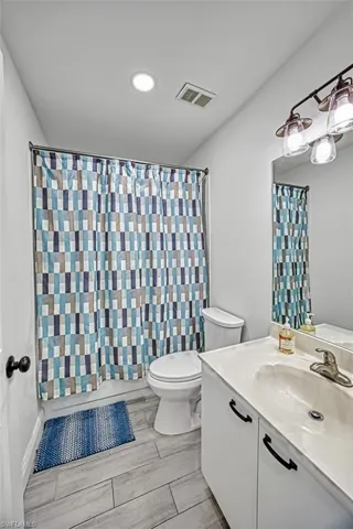 Bathroom featuring a shower with shower curtain, vanity, and toilet