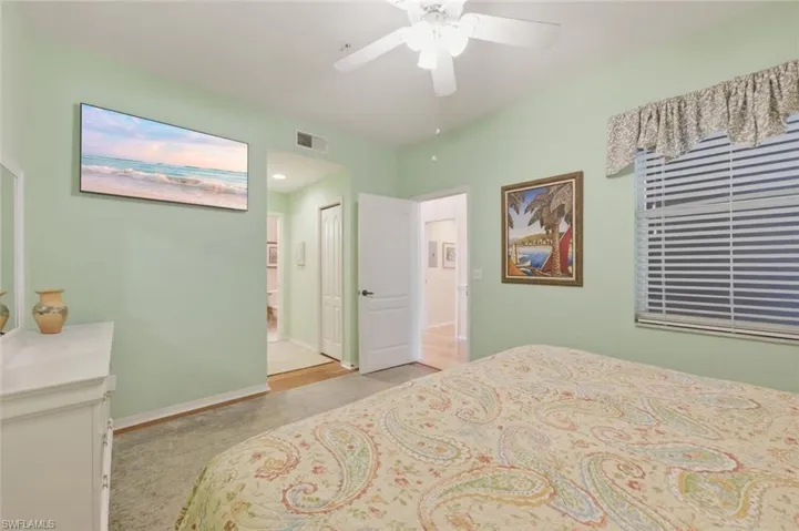 Bedroom featuring a ceiling fan, light colored carpet, and ensuite bathroom