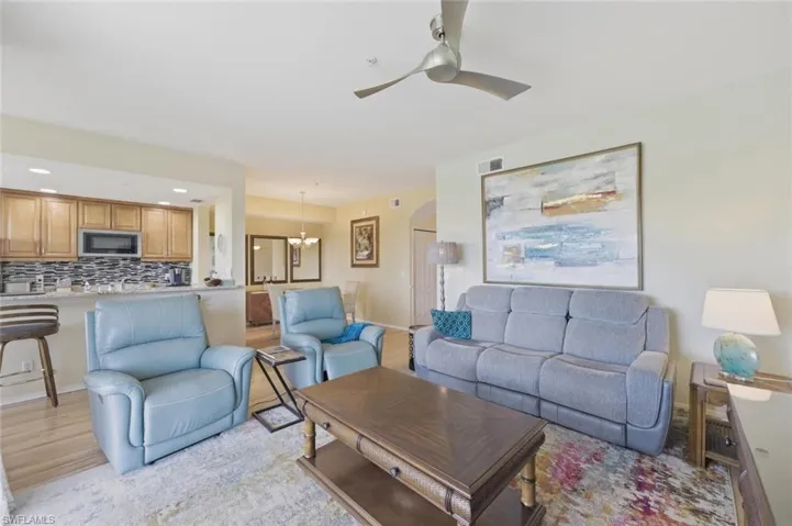 Living room featuring a ceiling fan, arched walkways, light wood-style floors, and recessed lighting