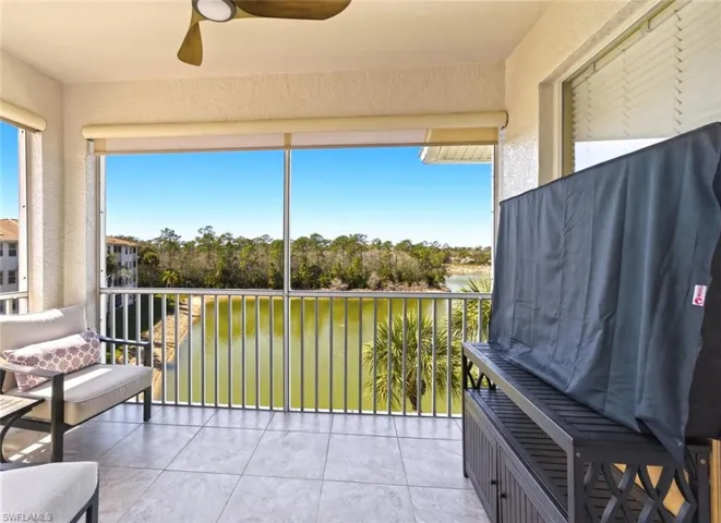 Sunroom featuring tile patterned floors, a textured wall, a water view, and view of scattered trees