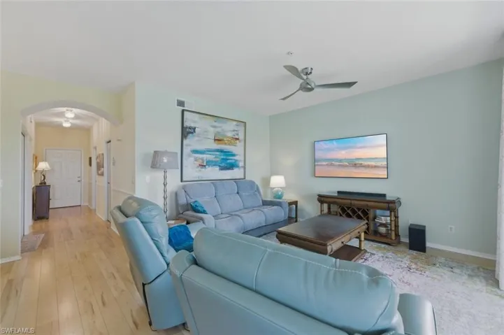 Living room featuring arched walkways, light wood-style floors, and ceiling fan