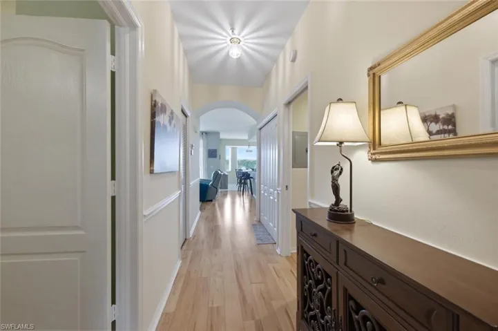 Hallway featuring arched walkways and light wood-style floors