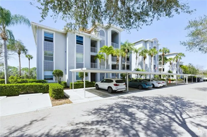 View of apartment building / complex featuring covered parking