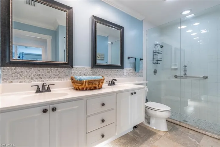 Bathroom featuring vanity, toilet, a shower with shower door, decorative backsplash, and ornamental molding