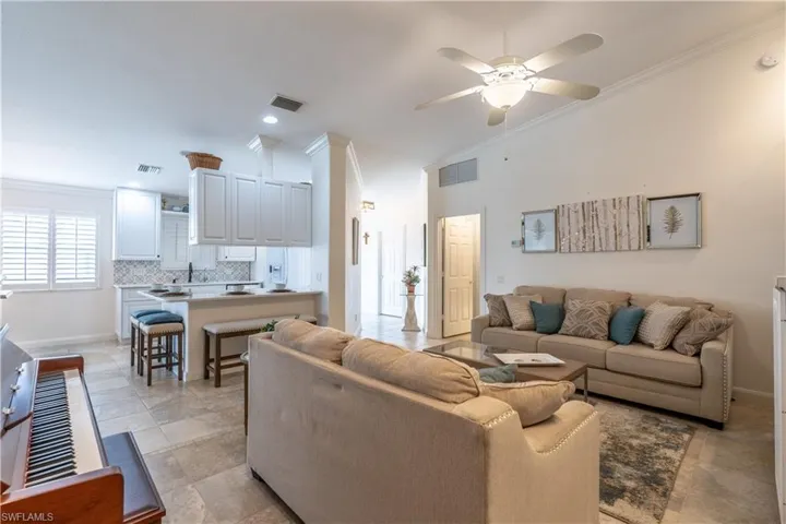 Living room with crown molding, vaulted ceiling, and ceiling fan