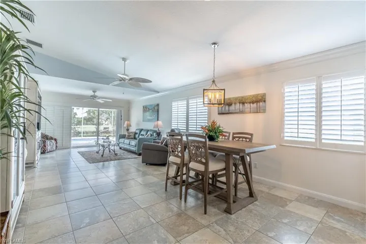 Dining area featuring lofted ceiling, ceiling fan with notable chandelier, and crown molding