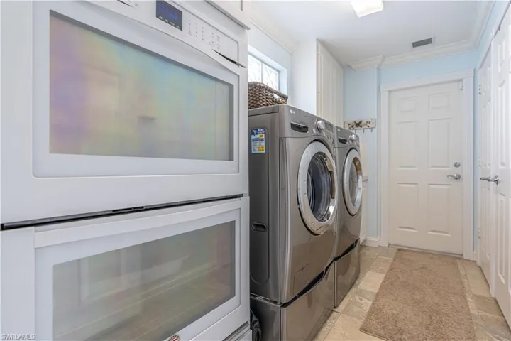 Laundry area featuring crown molding, light tile patterned floors, and washer and dryer