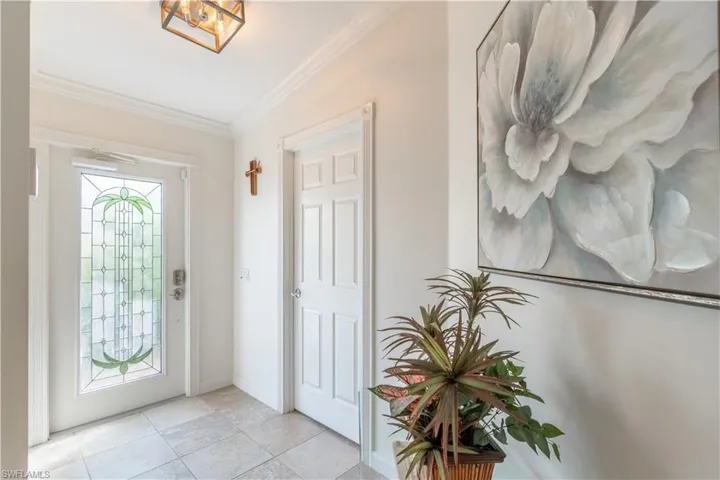 Tiled foyer featuring crown molding