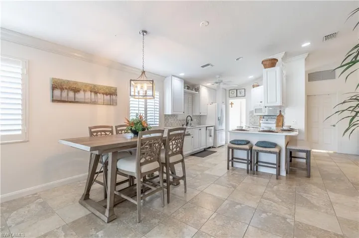 Dining space with plenty of natural light, ornamental molding, and ceiling fan with notable chandelier