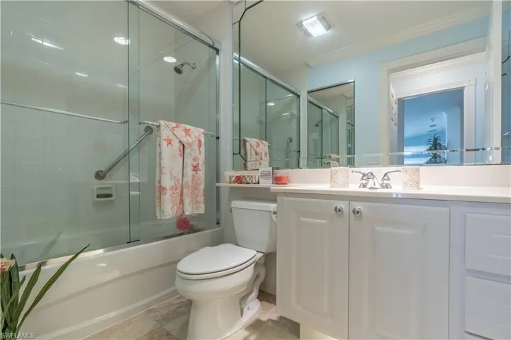 Full bathroom featuring tile patterned flooring, toilet, combined bath / shower with glass door, and vanity