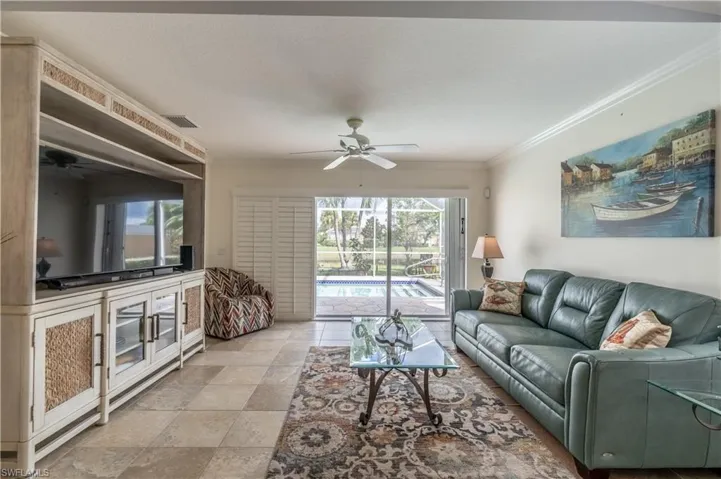 Living room featuring ceiling fan, crown molding, and a healthy amount of sunlight