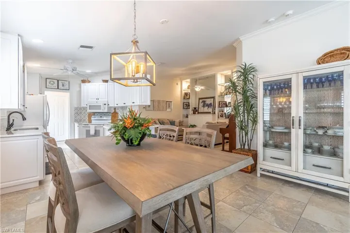 Dining area featuring ceiling fan with notable chandelier, crown molding, and sink