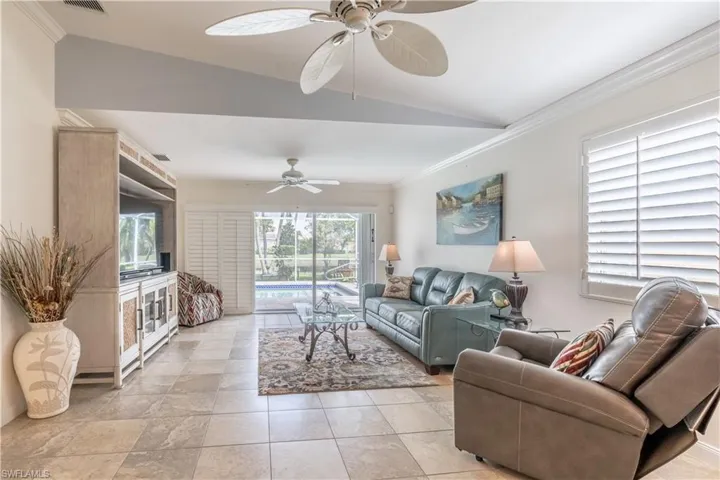 Living room with lofted ceiling, ceiling fan, and ornamental molding