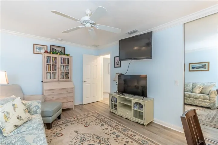 Living room with light wood-type flooring, ceiling fan, and ornamental molding