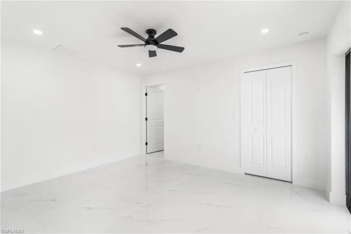 Unfurnished bedroom featuring recessed lighting, light marble finish flooring, a ceiling fan, and a closet