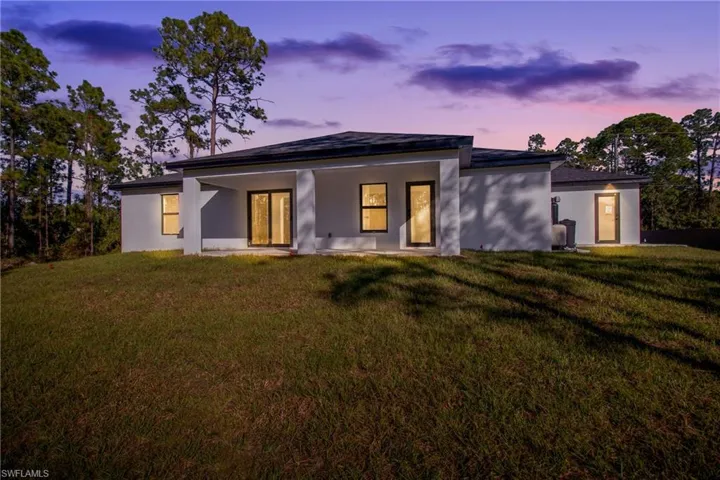 Back of property featuring a lawn, stucco siding, and a patio area